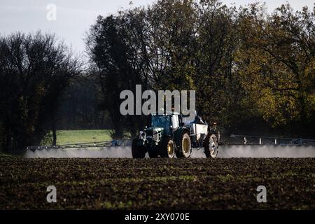 Trattamento fitosanitario su un appezzamento agricolo in autunno-inverno: Trattore con irroratrice in un campo, diffusione di pesticidi, fitofarmaceutica Foto Stock