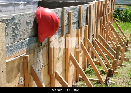 Concetto di costruzione di edifici. Foto ravvicinata del supporto per la casa in legno e del casco da costruzione Foto Stock