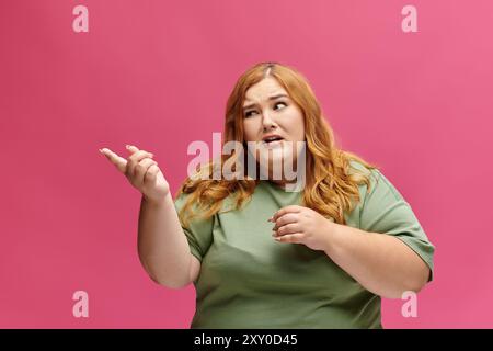 Una donna dai capelli rossi accesi si si muove lateralmente su uno sfondo rosa vivace. Foto Stock