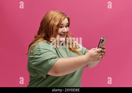 Una donna sorride brillantemente mentre guarda il suo telefono, tenendolo in entrambe le mani. Foto Stock