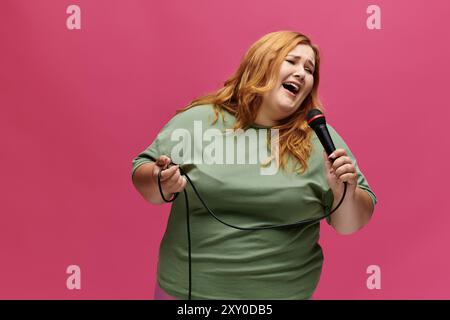 Una donna allegra, in camicia verde, canta con passione nel microfono Foto Stock