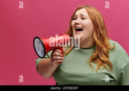 Una donna con lunghi capelli rossi sorride e grida attraverso un megafono. Foto Stock