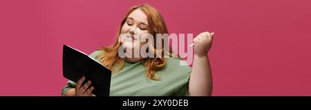 Una donna, vestita con un abbigliamento elegante, sorride mentre legge un libro e tiene in mano una penna. Foto Stock