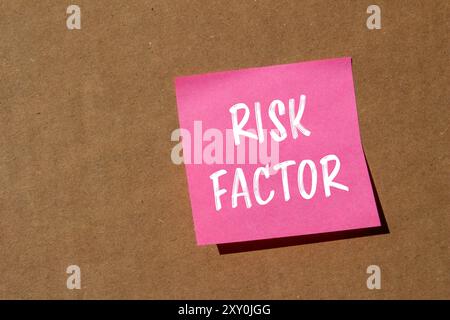 Messaggio sul fattore di rischio scritto su carta rosa con sfondo in cartone. Simbolo del fattore di rischio concettuale. Copia spazio. Foto Stock