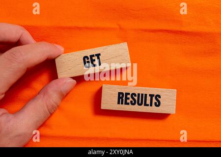 Ottenere il messaggio dei risultati scritto su blocchi di legno con sfondo arancione. Simbolo dei risultati concettuali. Copia spazio. Foto Stock