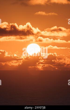 Lo splendido tramonto è stato catturato sull'oceano delle Azzorre, caratterizzato da vivaci cieli arancioni e spettacolari formazioni nuvolose intorno a un sole incandescente Foto Stock