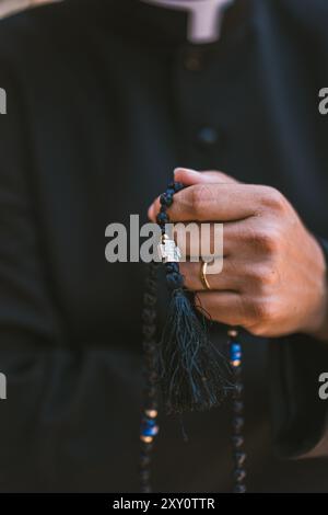 Primo piano ritagliato e irriconoscibile delle mani di un prete cattolico che tiene le perle di rosario ad Altea, Valencia, Spagna. Foto Stock