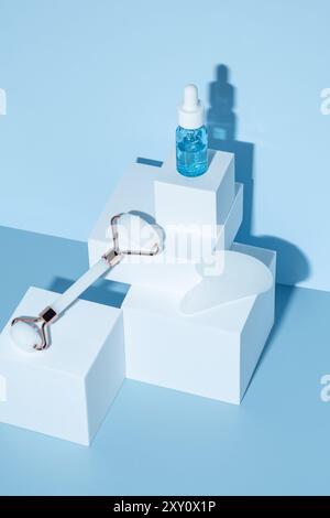 Una disposizione serena di utensili per la cura della pelle e una bottiglia di siero ialuronico su blocchi geometrici, che getta ombre morbide su sfondo blu. Aggiunge un tocco di lusso Foto Stock