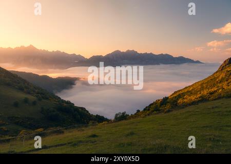 Viste mozzafiato dell'alba sui Picos de Europa, Cantabria, con colline ondulate e vette montuose circondate da nuvole. Un solitario, unrecogni Foto Stock