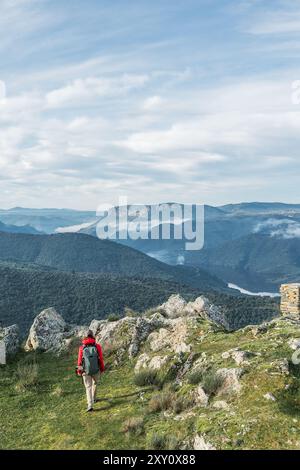 Una donna, vestita con l'attrezzatura da trekking, esplora i vibranti paesaggi di Vilvestre e Salamanca e ammira la vasta catena montuosa e i cieli sereni, embodyi Foto Stock