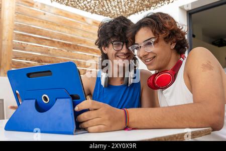 Una coppia gay felice condivide un momento di gioia mentre navighi insieme su un tablet a casa, mostrando amore e vita di tutti i giorni Foto Stock