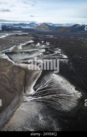 Spettacolare scatto aereo che cattura il vasto e aspro terreno delle Highlands islandesi, con vorticosi motivi in bianco e nero delle terre vulcaniche Foto Stock