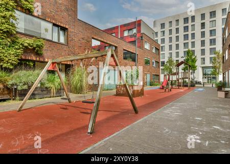 Parco giochi urbano vuoto circondato da moderni edifici di appartamenti in una giornata di sole. Foto Stock