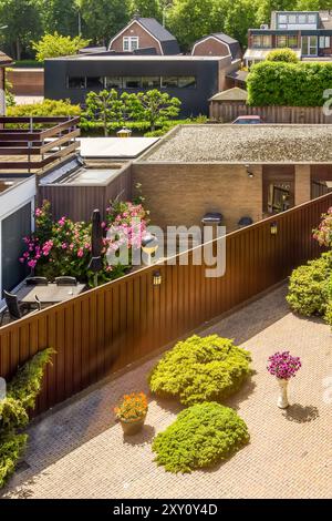 Vista aerea di un giardino urbano splendidamente paesaggistico con un accogliente patio, piante fiorite e arbusti rifiniti, che mostrano un elegante design all'aperto. Foto Stock