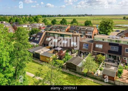 Una vista dall'alto di una tranquilla area suburbana, che presenta una linea di case con giardini sul retro adiacenti a campi verdi aperti. Foto Stock