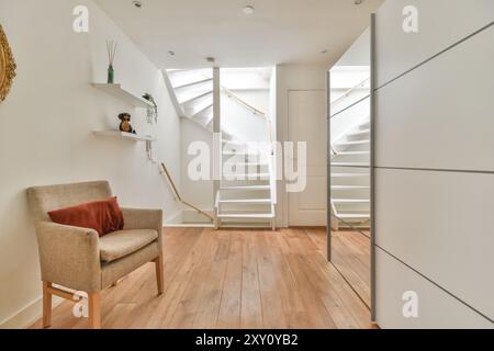 Interni luminosi e moderni, con pavimento in legno, mobili minimalisti e una scala bianca con un elegante corrimano. Foto Stock