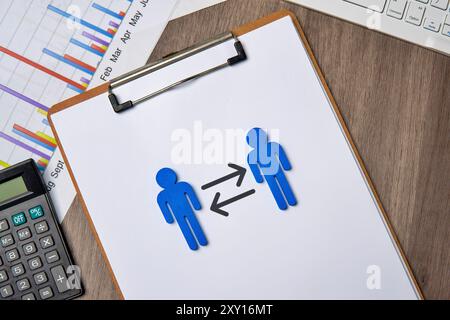 Due figure blu su una clipboard, rivolte l'una verso l'altra con frecce che puntano in entrambe le direzioni. Ciò simboleggia il concetto di rotazione del lavoro. Foto Stock