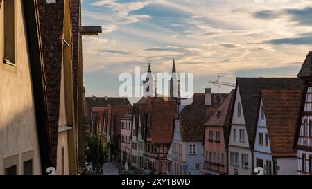 Mentre il sole tramonta su Rothenburg ob der Tauber, i visitatori si snodano lungo le pittoresche stradine costeggiate da edifici storici Foto Stock