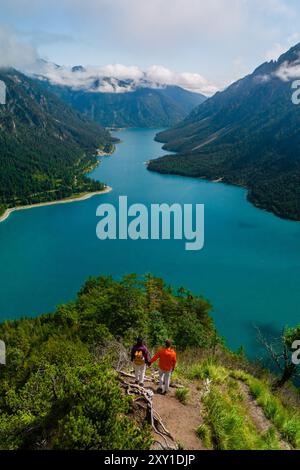 Un paio di passeggiate mano nella mano lungo un sentiero panoramico, che si affaccia sulle tranquille acque del lago Plansee circondato da maestose montagne. Plansee Austria Foto Stock