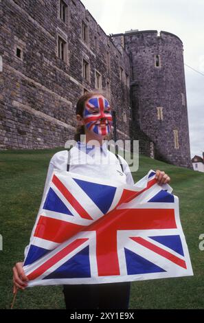 Matrimonio reale del Principe Edoardo e Sophie Rhys-Jones al Castello di Windsor, Windsor, Berkshire, Inghilterra 19 giugno 1999. Una giovane donna con il suo volto dipinto come Union Jack tiene una bandiera di fronte al Castello di Windsor, potendo formare una fotografia ricordo. 1990 UK HOMER SYKES Foto Stock