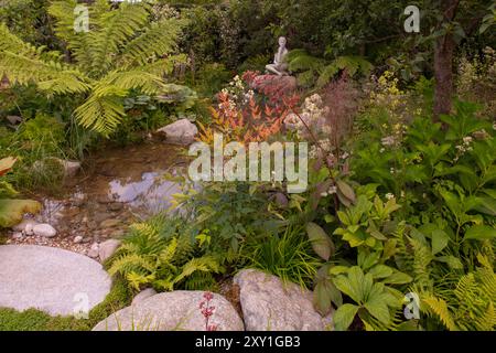 Una statua accanto ad uno stagno circondato da piante che amano l'ombra nel cammino del St James Garden, un giardino principalmente boscoso progettato da Nilfer Danis. Foto Stock