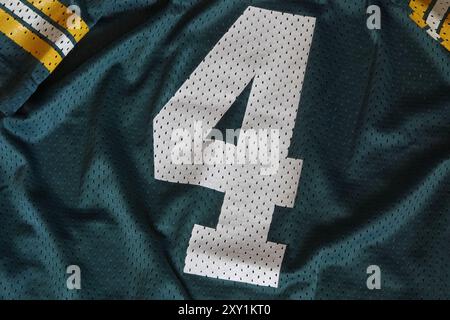 Il numero 4 viene visualizzato da vicino su una maglia sportiva in maglia verde, bianca e gialla. Foto Stock