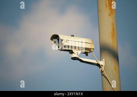 telecamera di sicurezza appesa al polo di alimentazione isolata su sfondo blu Foto Stock