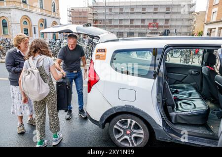 Pisa Italia, Piazza della stazione, stazione ferroviaria centrale di Pisa, taxi che raccoglie i passeggeri in arrivo, autista che carica bagagli SUV, donna Foto Stock