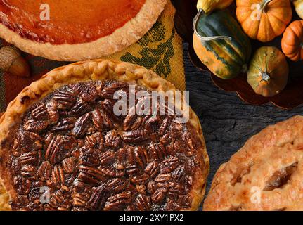 Pecan, zucca e torta di mele del giorno del Ringraziamento su un tavolo rustico con dolci decorativi. Foto Stock