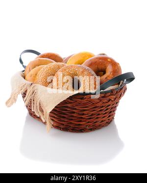 Un cestino di bagel assortiti su una superficie bianca con riflessi. Una varietà di bagel tra cui: Uova, sesamo, cereali multipli, cipolla e cannella. Foto Stock