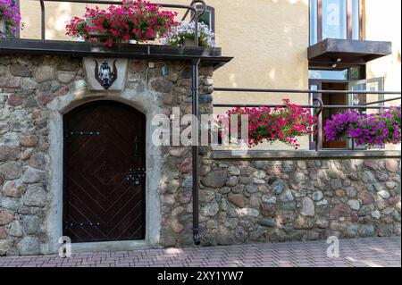 Una porta rustica in legno incorniciata da un muro di pietra adornato da vibranti fiori in un ambiente all'aperto sereno Foto Stock