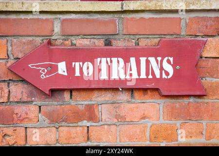 Cartello con freccia rossa d'epoca sul muro di mattoni che punta verso la stazione ferroviaria. Foto Stock