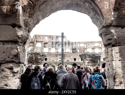 All'interno del Colosseo: Turisti e una maestosa Croce tra antiche rovine Foto Stock