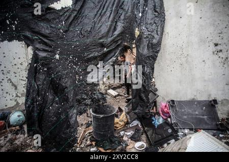 Tulkarm, Palestina. 27 agosto 2024. I palestinesi oltrepassano i relitti causati dall'attacco aereo israeliano al campo profughi di Nour Shams. L'aeronautica militare israeliana ha bombardato un edificio nel campo profughi di Nour Shams, distruggendo diverse case e strade vicine e uccidendo cinque giovani uomini. Credito: SOPA Images Limited/Alamy Live News Foto Stock