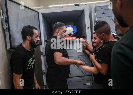 Tulkarm, Palestina. 27 agosto 2024. (NOTA A CURA: L'immagine raffigura la morte)i parenti si riuniscono intorno al corpo di uno dei cinque palestinesi uccisi in un attacco aereo israeliano sul campo profughi di Nour Shams. Credito: SOPA Images Limited/Alamy Live News Foto Stock