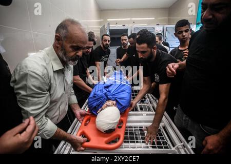 Tulkarm, Palestina. 27 agosto 2024. (NOTA A CURA: L'immagine raffigura la morte)i parenti si riuniscono intorno al corpo di uno dei cinque palestinesi uccisi in un attacco aereo israeliano sul campo profughi di Nour Shams. Credito: SOPA Images Limited/Alamy Live News Foto Stock