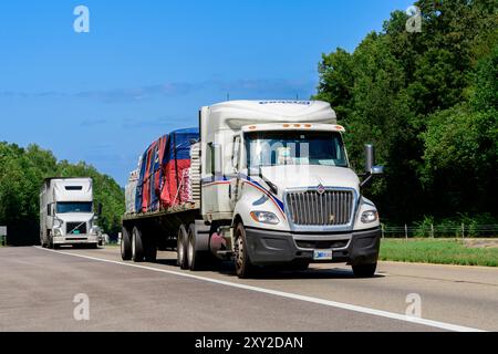 Knoxville, Tennessee, Stati Uniti – 20 agosto 2024: Colpo orizzontale di un carro a pianale carico pesante che conduce il traffico lungo un'interstate del Tennessee. Ciao Foto Stock