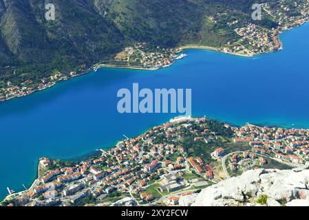 Vista aerea della baia di Cattaro, Montenegro: Acque blu dell'Adriatico, la costa tortuosa e le case delle città di Dobrota, Muo e Prcanj. Foto Stock