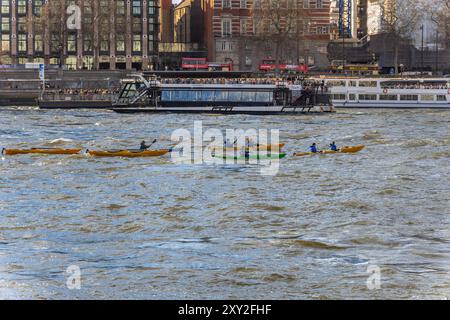 Amici e famiglie che praticano sport acquatici in kayak e canoe sul fiume Tamigi e imbarcazioni da diporto turistiche e autobus turistici in barca Foto Stock