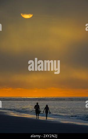 Isola di Palms, Stati Uniti. 27 agosto 2024. Una passeggiata di coppia lungo la spiaggia mentre il sole fatica a rompere una pesante nebbia marittima sull'Oceano Atlantico, 27 agosto 2024 a Isle of Palms, South Carolina. Crediti: Richard Ellis/Richard Ellis/Alamy Live News Foto Stock