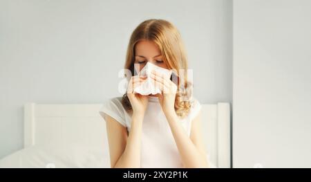 Ritratto di una donna malata che starnutisce soffia il naso usando il tessuto Foto Stock