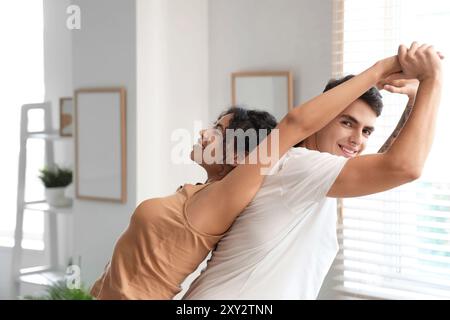 Giovane coppia che pratica yoga insieme a casa Foto Stock