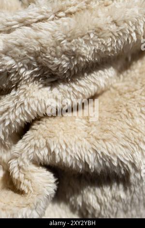 Sfondo decorativo per pubblicità o prodotti.Wallpeper.spazio per copia. Texture di coperta shaggy in tonalità beige. Primo piano di una coperta di pelliccia. Foto Stock