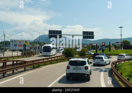 Progni, Italia - 8 giugno 2023: I veicoli navigano in un trafficato interscambio autostradale, con colline lontane incorniciate da un cielo azzurro. Foto Stock