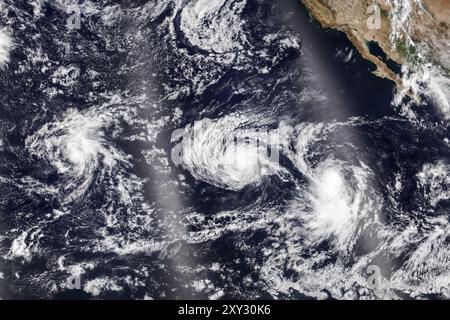 Oceano Pacifico, Stati Uniti. 27 agosto 2024. L'immagine satellitare del NASA Earth Observatory mostra gli uragani tripli nel bacino del Pacifico settentrionale, 25 agosto 2024. L'uragano Hone, a sinistra, ha pascolato le Hawaii come una tempesta di categoria uno mentre l'uragano Gilma, a categoria 3, gira al largo della costa di Baja, seguito da vicino dalla tempesta tropicale Hector, a destra. Crediti: Earth Observatory/NASA/Alamy Live News Foto Stock