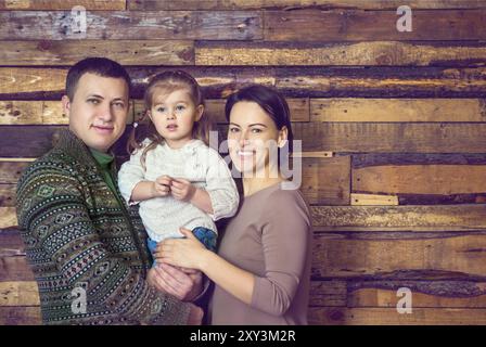 Felice ritratto di famiglia con la figlia piccola sullo sfondo di legno Foto Stock