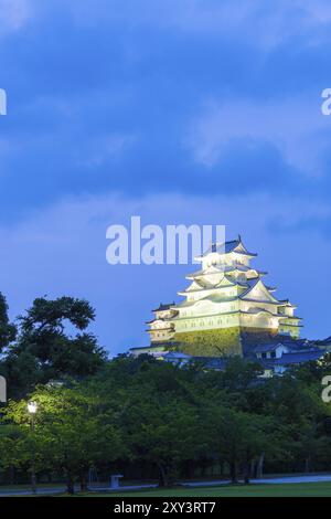Cielo blu scuro dietro illuminato Himeji-jo, uno dei 12 castelli originali rimasti, sopra un parco al crepuscolo a Himeji, in Giappone, dopo 2015 lavori di ristrutturazione Foto Stock