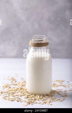 Vegan senza prodotti caseari Latte di avena e fiocchi bianchi su sfondo di legno Foto Stock