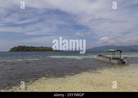 Fotografia di una piccola barca per immersioni ancorata di fronte a una piccola isola nelle Isole Salomone Foto Stock