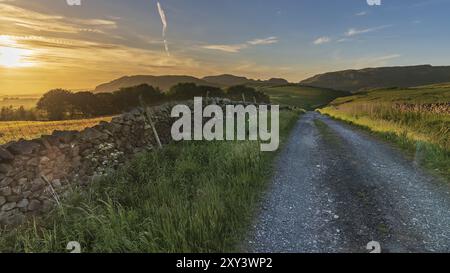 Tramonto su una strada rurale nel Yorkshire Dales vicino a Settle, North Yorkshire, Inghilterra, Regno Unito Foto Stock